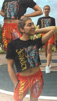 a woman wearing a t - shirt and shorts on a basketball court